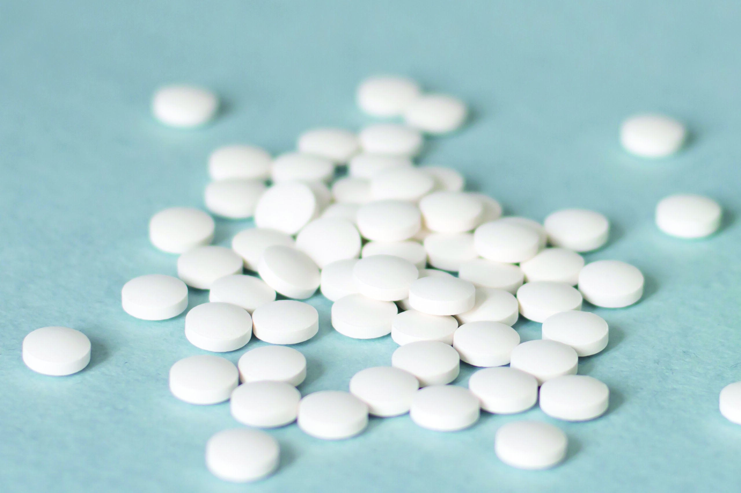 Medication white round tablets arranged isolated on blue background, close-up of tablets. Concept of health, treatment, choice, healthy lifestyle.