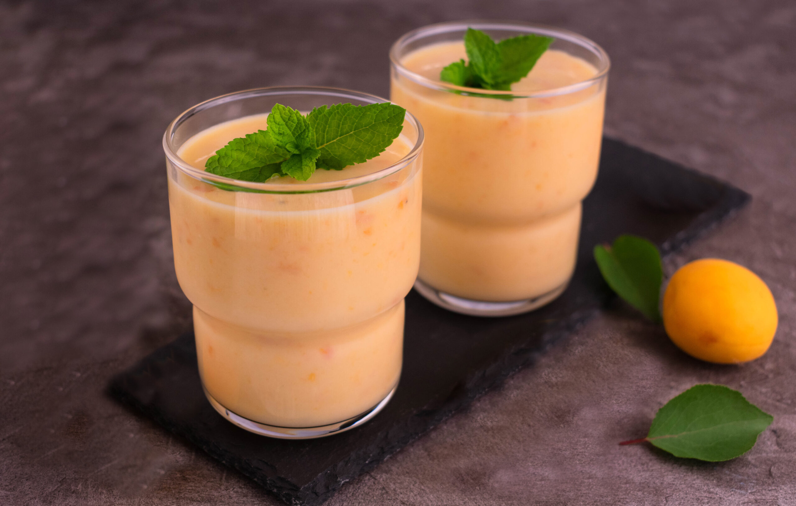Apricot smoothie on a gray background. Two glasses of apricot smoothie.