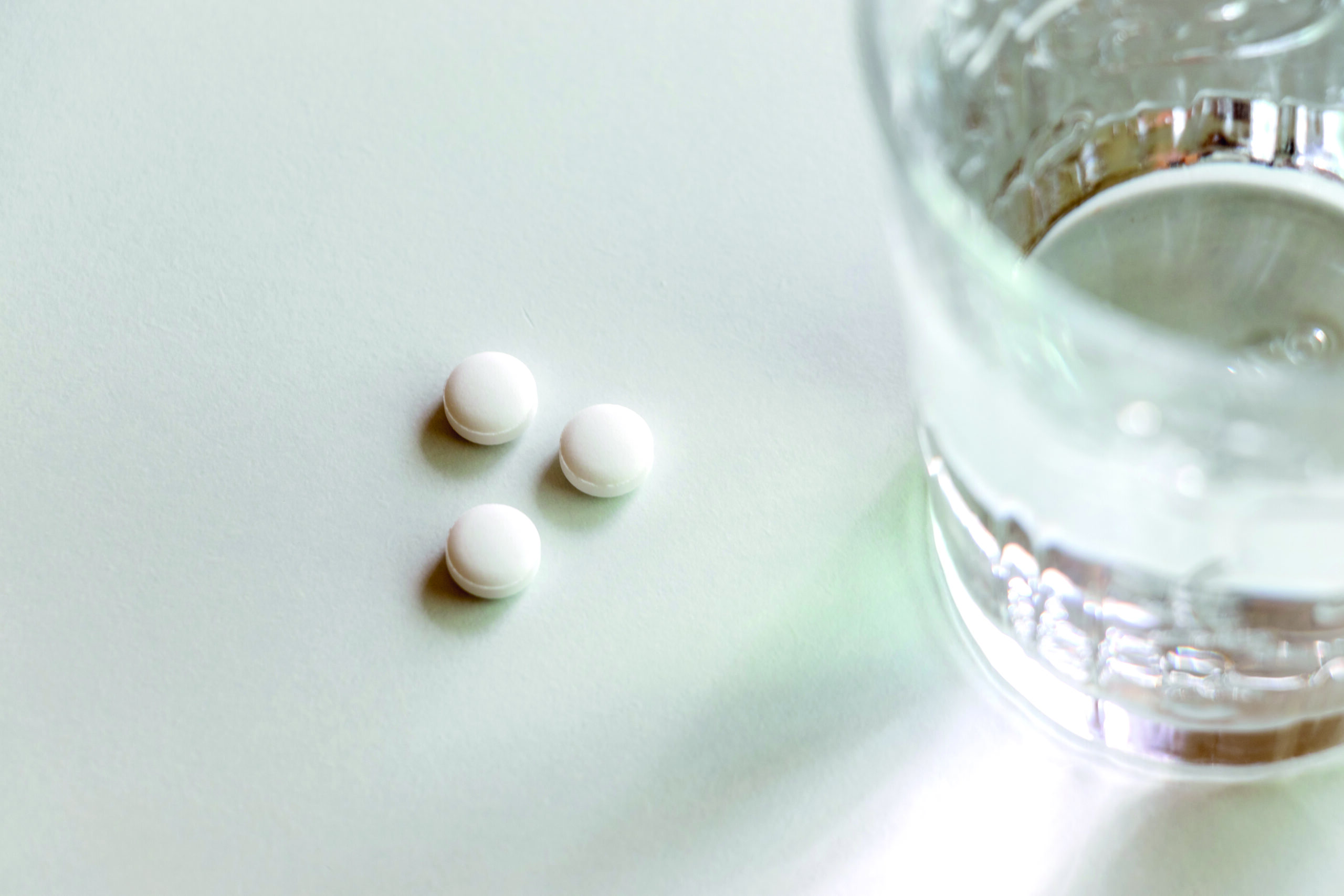White tablets and a glass of water