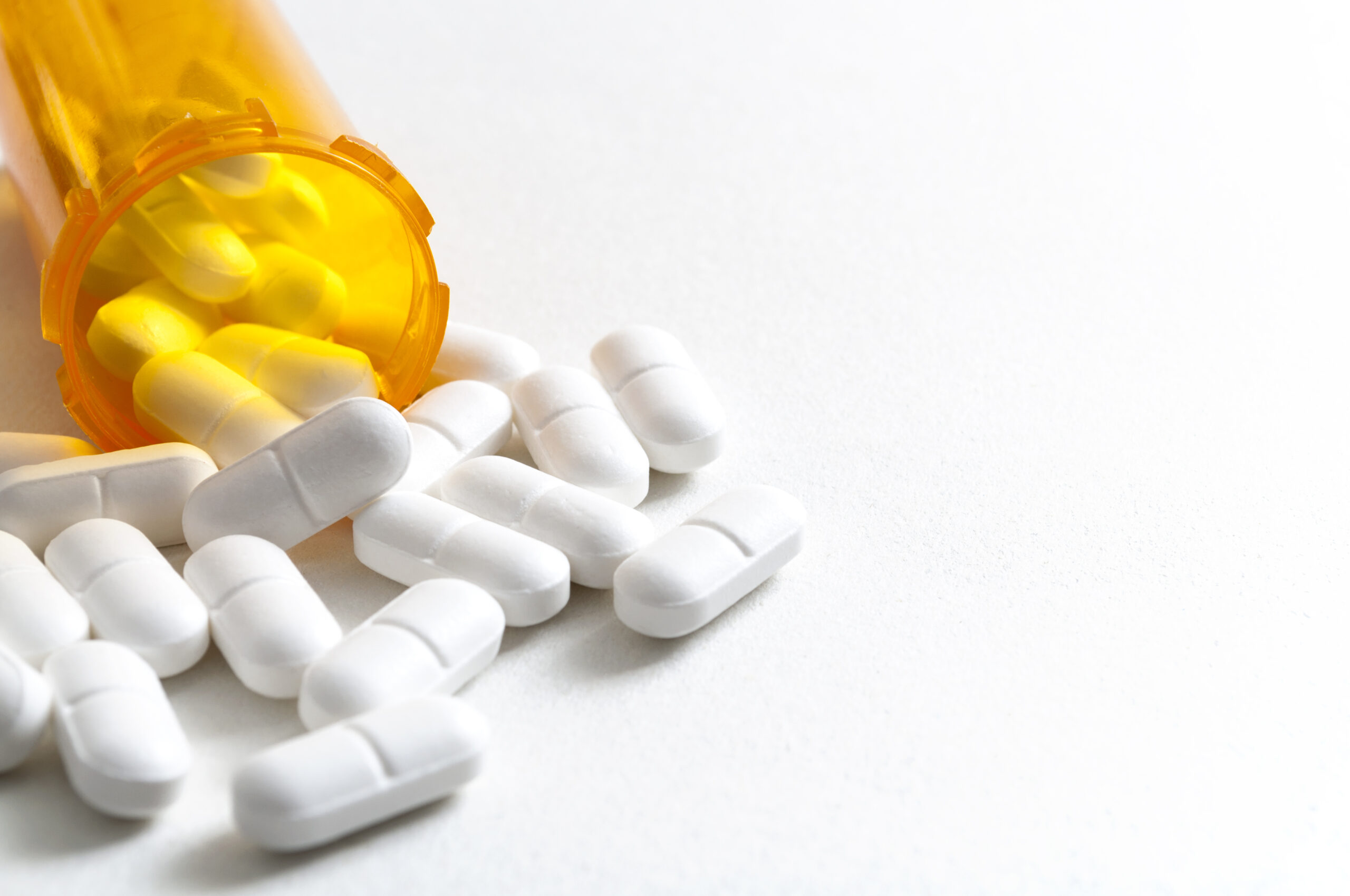 Hydrocodone capsules spilling out of a prescription bottle with copyspace