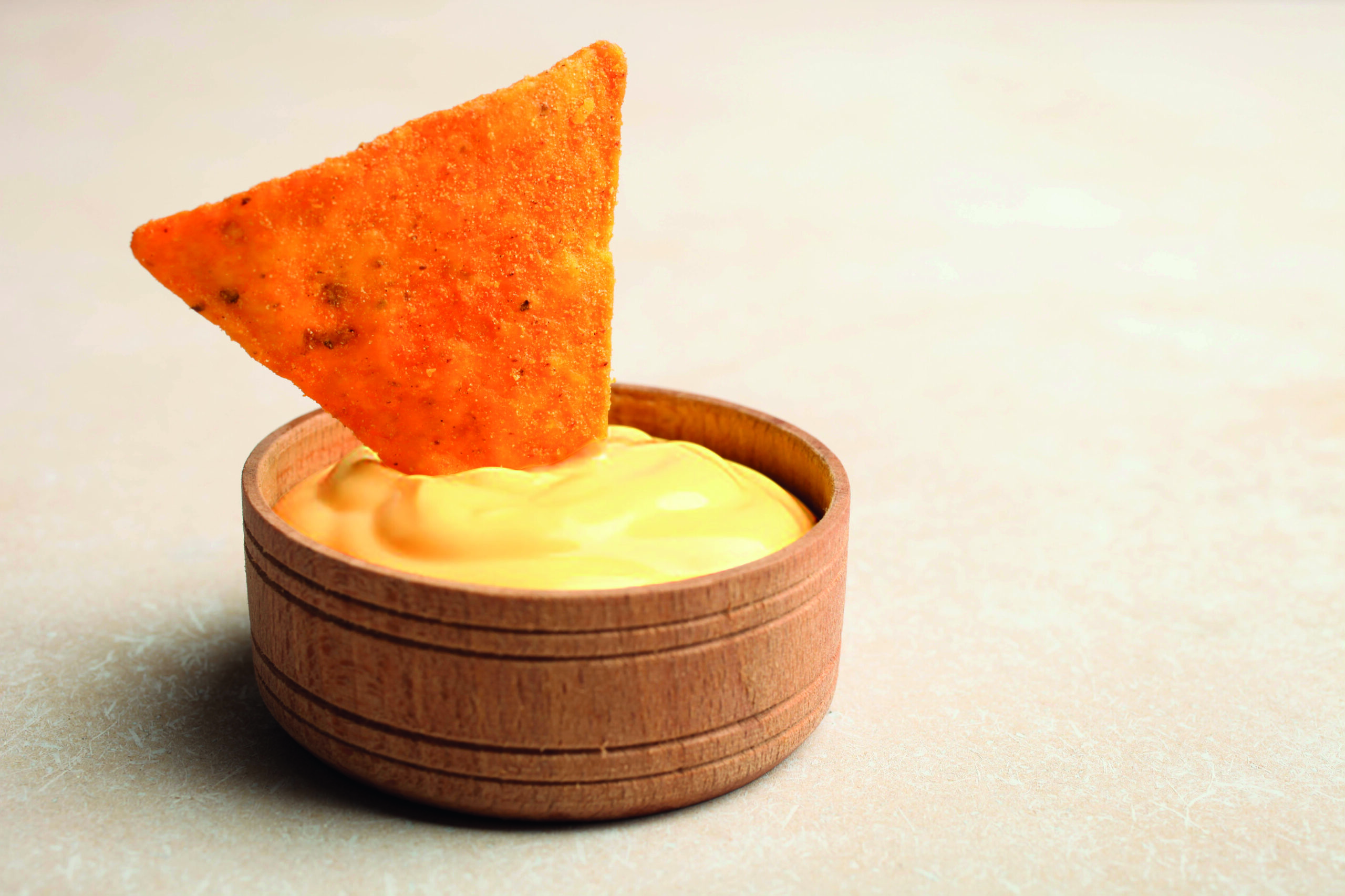 Mexican crispy snack, nachos chips and cheese sauce on neutral background.